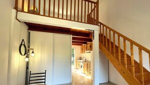 Ein Essbereich mit Tisch und Stühlen, im Hintergrund eine Küche und eine Holztreppe.