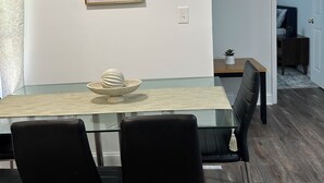 Un comedor con una mesa de vidrio, sillas negras y un cuenco decorativo.