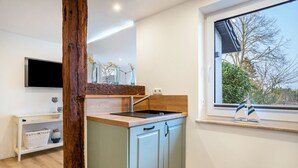 Eine moderne Küche mit Holzbalken, einer integrierten Spüle und einem Fenster mit Blick auf Bäume.