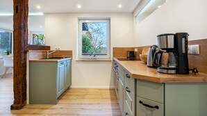 Eine moderne Küche mit einer zentralen Kochinsel, Holzelementen und einem Fenster, das natürliches Licht hereinlässt.