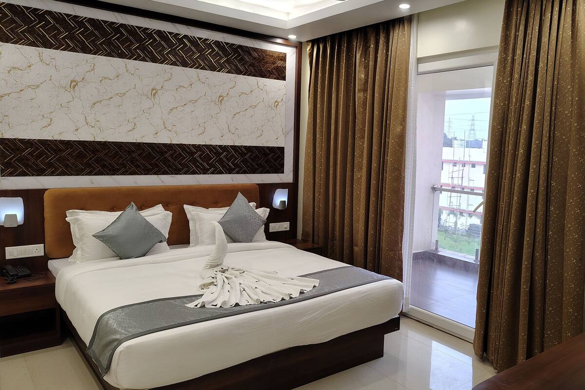 Une chambre d’hôtel avec un grand lit, un mur décoré d’un motif imitant le marbre, une vue sur l’extérieur et un tableau encadré accroché au mur.