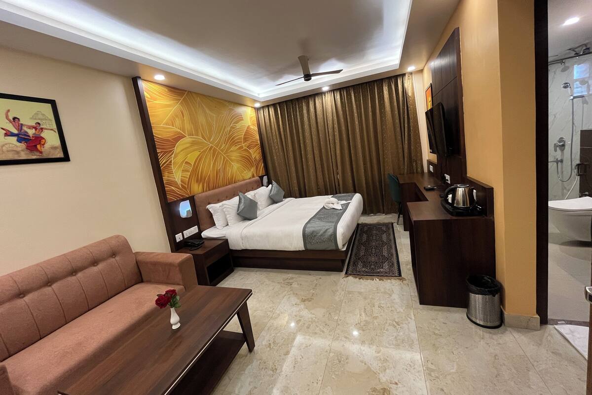 Une chambre d’hôtel moderne équipée d’un lit, d’un canapé, d’un bureau, d’une télévision et d’un espace douche.