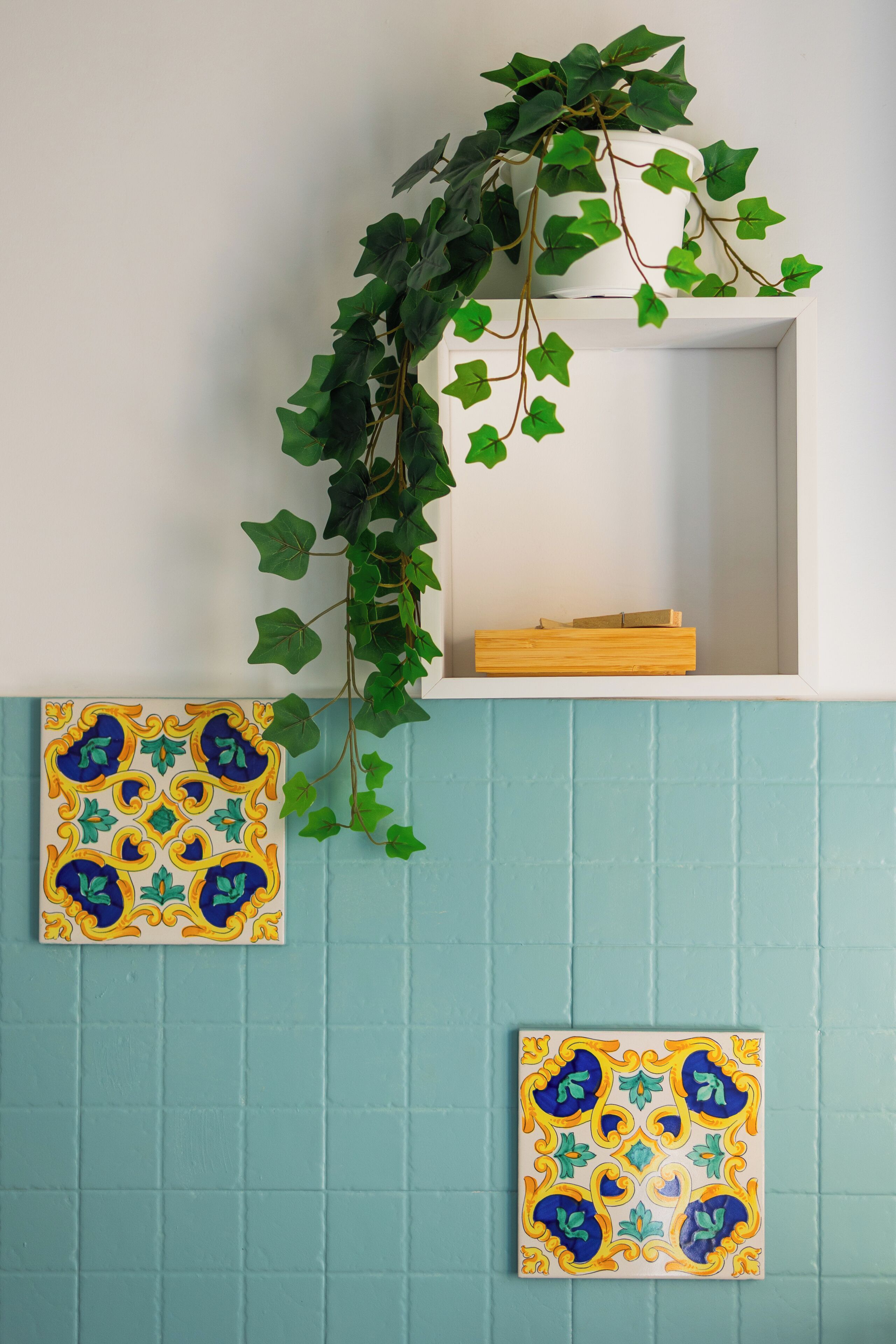 A bathroom with a tiled wall, a white sink, and a mirror.