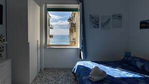 Una camera da letto con un letto, una finestra vista mare e un piccolo balcone.