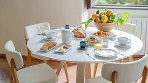 Una tavola per la colazione con una ciotola di frutta, croissant e una caffettiera.