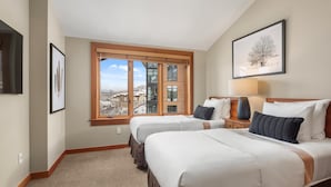 Habitación de hotel con dos camas, un ventanal con vista a la ciudad y obras de arte enmarcadas en las paredes.