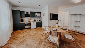 A modern kitchen with dark cabinets, a wooden dining table, and a TV mounted on the wall. - Modern apartment in Viernheim (Viernheim)