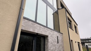 A modern two-story building with large windows, a brick facade, and a paved entrance area. - Modern apartment in Viernheim (Viernheim)