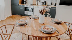 A modern kitchen with dark green cabinets, a wooden dining table set for six, and a large window overlooking the room. - Modern apartment in Viernheim (Viernheim)