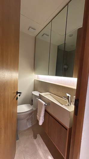 Ein kleines Badezimmer mit Toilette, Waschbecken und Spiegel.