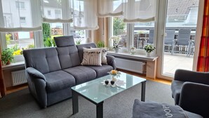 Una sala de estar moderna con un sofá gris, una mesa de centro de vidrio y vistas al exterior.