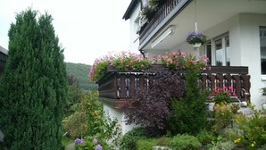 Un edificio con balcón, pared de piedra y varias plantas.