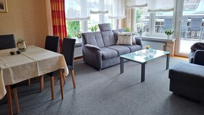 Una sala de estar moderna con un sofá, una mesa de centro de vidrio y una mesa de comedor con sillas.