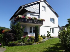 A two-story house with a balcony, surrounded by a well-maintained garden. - Holiday Apartment 'Waltraud, 105 sqm' with Panoramic View, Private Terrace & Wi-Fi (Brilon)