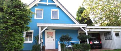 A two-story house with a blue exterior and white trim, a front porch, and a garage.