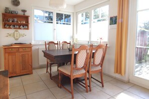 A dining area with a wooden table and chairs, a cabinet, and a window with curtains. - A quiet and light-flooded vacation apartment on the first floor (Wustrow)