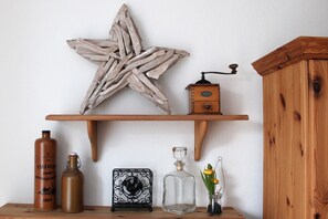 A wooden shelf with a rustic star decoration, a vintage radio, a metal rooster, a glass vase with flowers, and two bottles. - Vacation between sea&Bodden (Ahrenshoop)