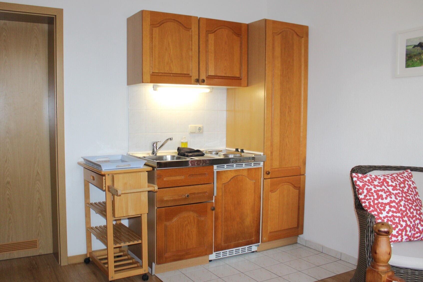 Een kleine keuken met houten kastjes, een spoelbak en een fornuis.