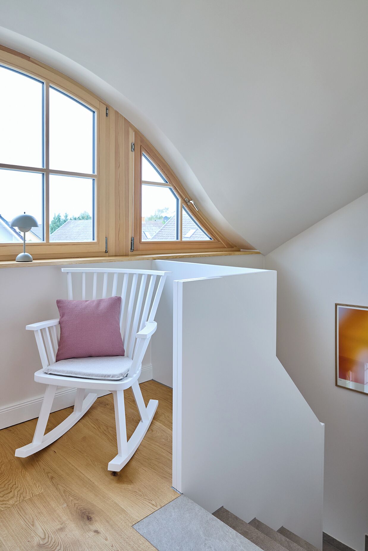 Ein gemütliches Schlafzimmer im Dachgeschoss mit Schaukelstuhl, Fenster und einem ungehinderten Blick nach draußen.