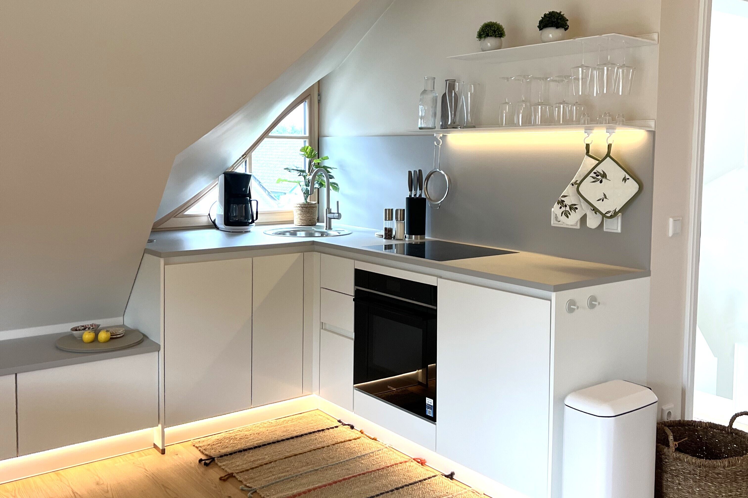 Eine moderne Küche mit Einbauofen, Spüle und einem Fenster, das für natürliches Licht sorgt.
