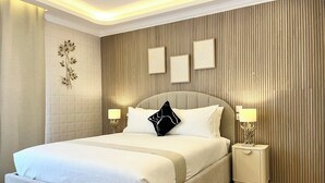 Quarto moderno com uma cama grande, duas mesas de cabeceira com luminárias e um painel decorativo na parede.