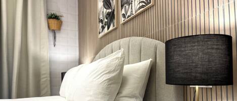 A neatly made bed with white linens and a gold lamp with a monkey base.