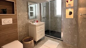 Um banheiro moderno com box de vidro, toucador branco e vaso sanitário.