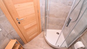 Eine Holztür mit Metallbeschlägen und einer Duschkabine mit Duschkopf.