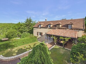 A two-story house with a tiled roof, a patio with outdoor furniture, and a well-maintained garden. - Spacious Family Home with Pool for 12 (Sarlat-la-Canéda)