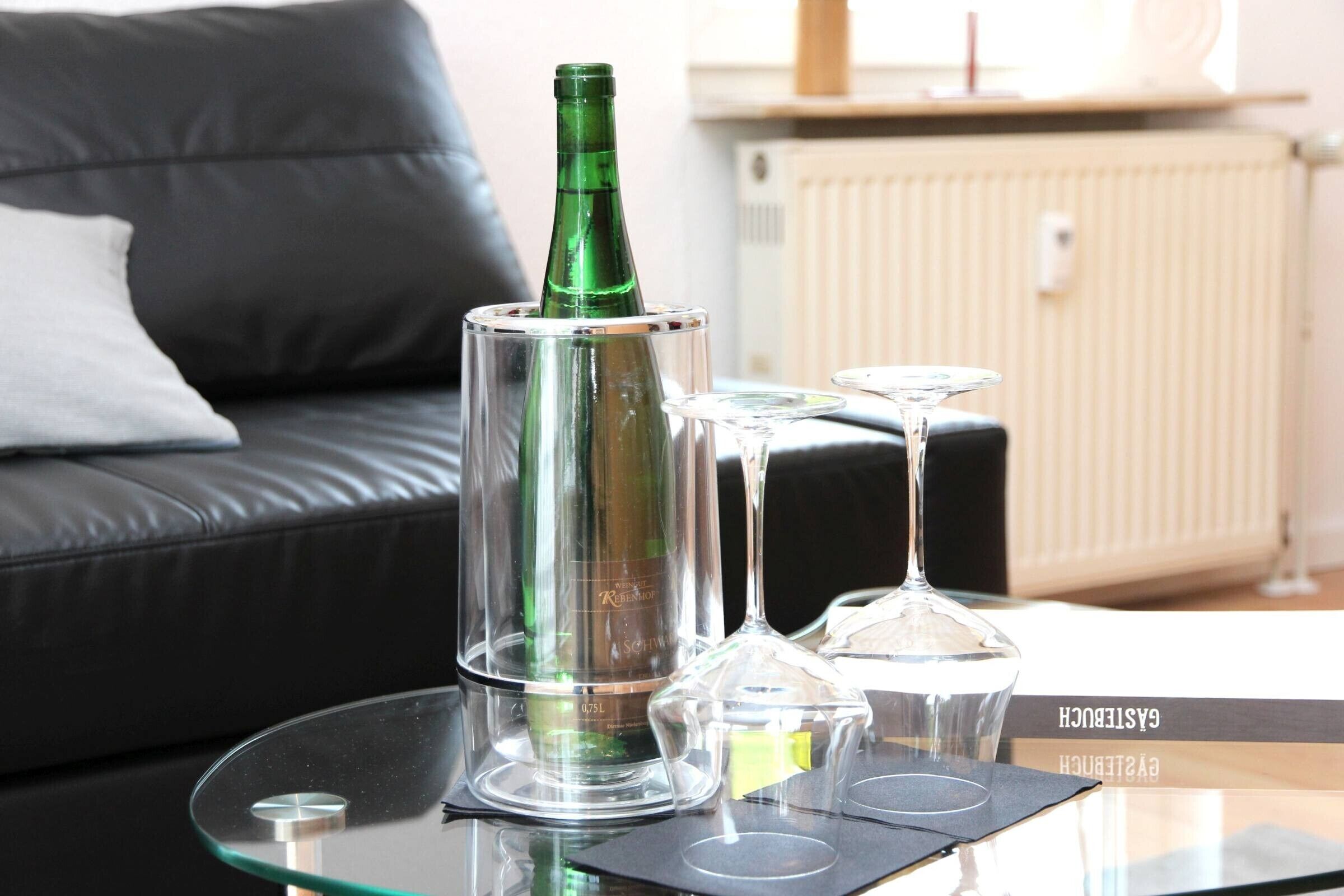 Une bouteille en verre sur une table en verre, avec deux verres à vin transparents.