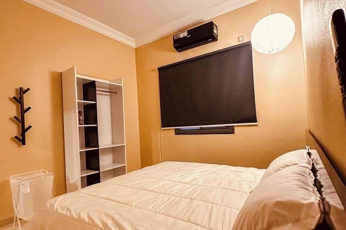 Een slaapkamer met een bed, een aan de muur bevestigde televisie, een kledingkast en een nachtkastje.