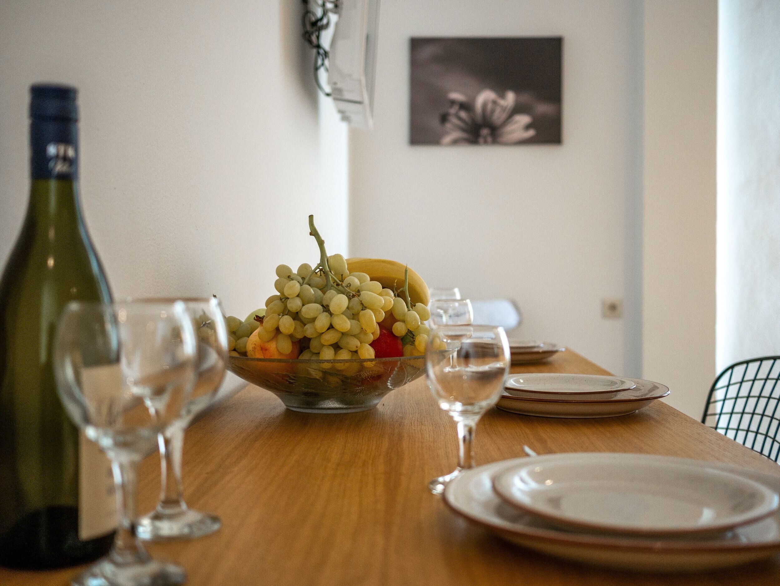 Een eettafel met een fruitschaal, wijnglazen en borden.