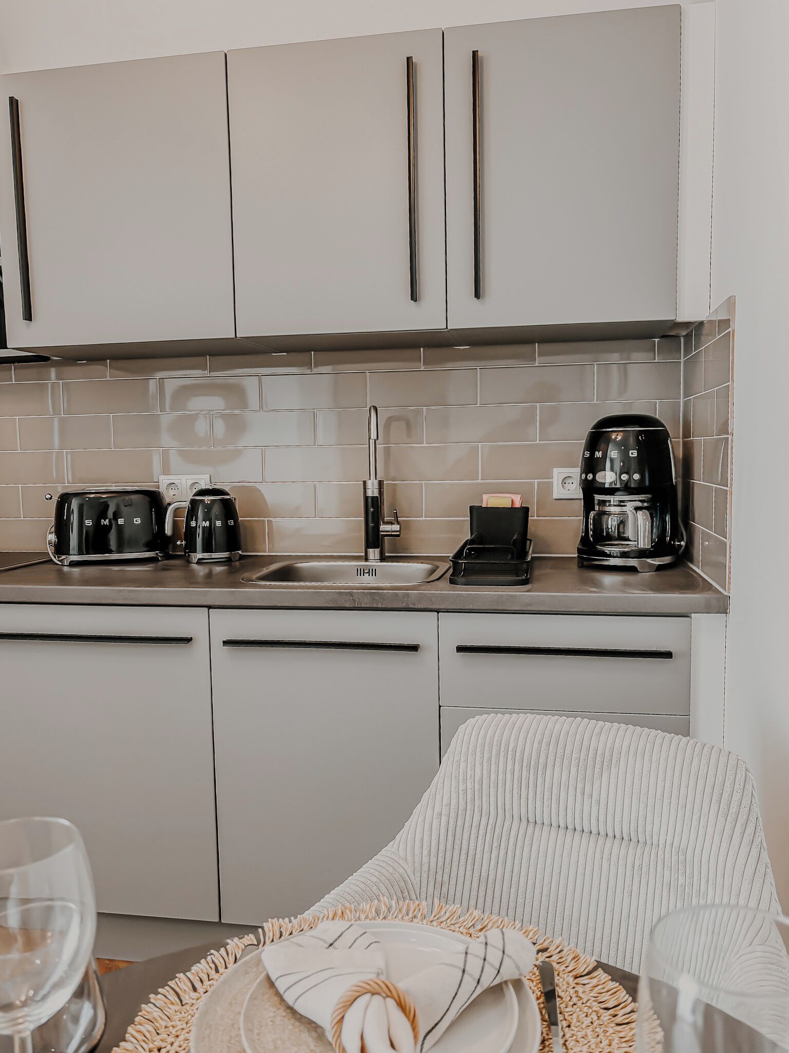 Eine moderne Küche mit weißen Schränken, einer gefliesten Spritzschutzwand und zwei Kaffeemaschinen.