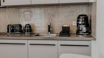 Eine moderne Küche mit weißen Schränken, einer gefliesten Spritzschutzwand und zwei Kaffeemaschinen.