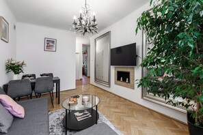 Ein modernes Wohnzimmer mit einer Couch, einem Esstisch, Stühlen, einem Kamin und einem großen Spiegel.
