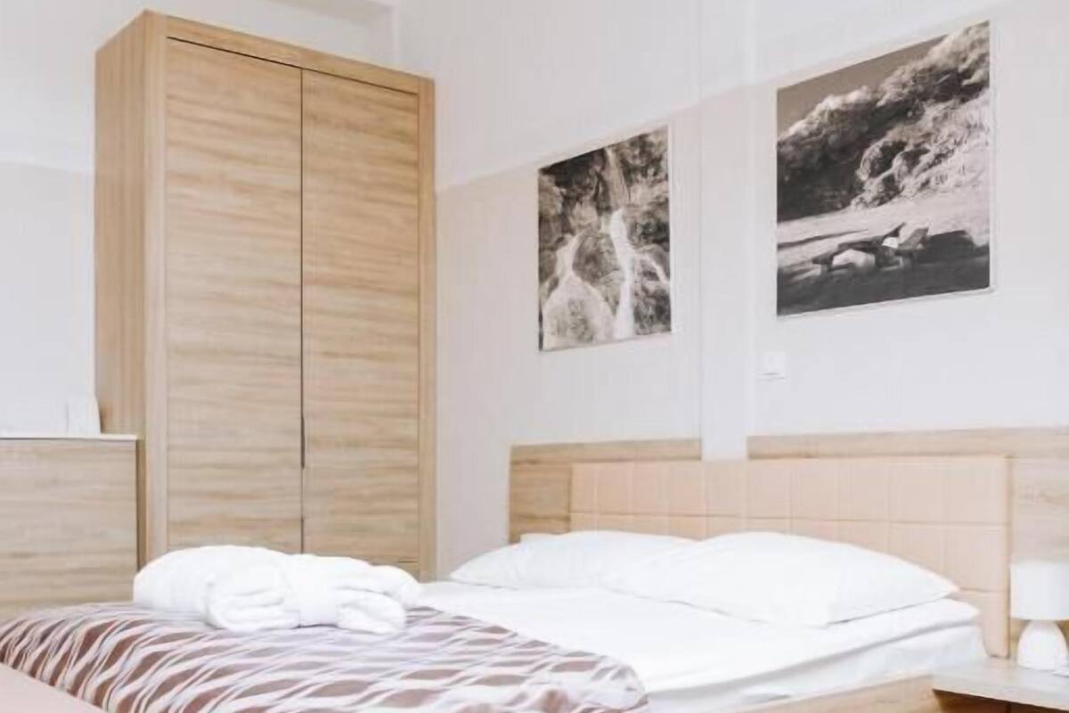 Un dormitorio moderno con un armario de madera, una cama con ropa de cama estampada y dos fotografías blanco y negro en la pared.