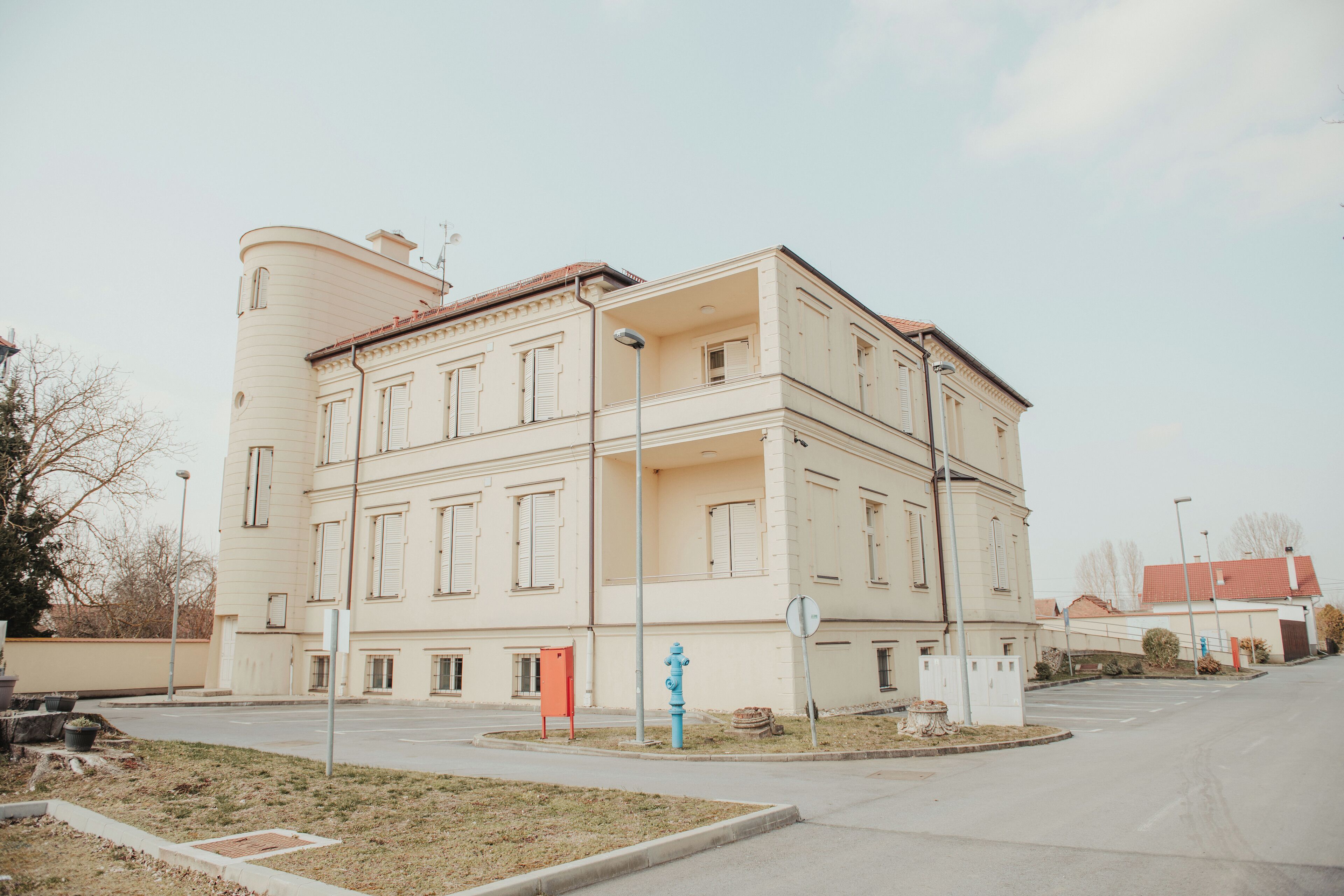 A multi-story building with a symmetrical facade, a central entrance, and a small courtyard with a blue fire hydrant.