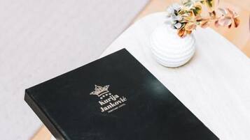 Een zwart boek met de titel 'Kurija Janković' op een witte tafel, met een witte vaas met bloemen.
