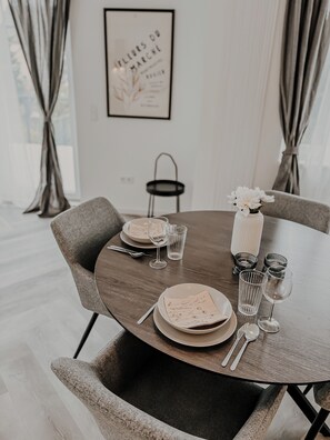 Una mesa de comedor dispuesta con platos, vasos y cubiertos, rodeada de sillas.