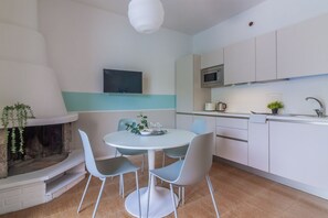 A modern kitchen with white cabinets, a microwave, and a built-in oven. There is a dining area with a round table and four chairs.