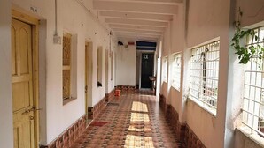 A corridor with patterned flooring, doors, and windows with bars. - Kriya Yoga Wellness (Kakdwip)