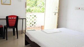 A room with a bed, a desk, and a chair. - Kriya Yoga Wellness (Kakdwip)