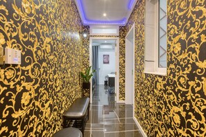 A narrow hallway with ornate black and gold wallpaper, a bench, and a door leading to another room. - AzureGold Apartment (Senglea)