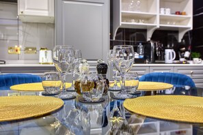 A dining table set with clear glassware and a bottle, surrounded by blue chairs and yellow placemats. - AzureGold Apartment (Senglea)