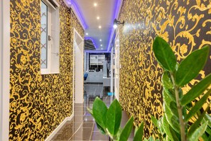 A hallway with patterned wallpaper and a view into a kitchen area. - AzureGold Apartment (Senglea)