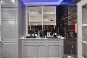 Eine Küche mit grauen Schränken, einer Kaffeestation und einem Regal voller Küchenutensilien.