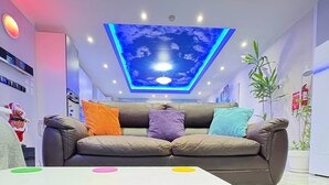 A modern living room with a sofa, pillows, a table, and a ceiling with a light fixture. - Azure Apartment (Senglea)