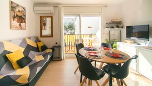 A modern living room with a sofa, dining table, chairs, and a TV. - WELCS APARTMENT 295 EMP with community pool (Rosas / Roses)
