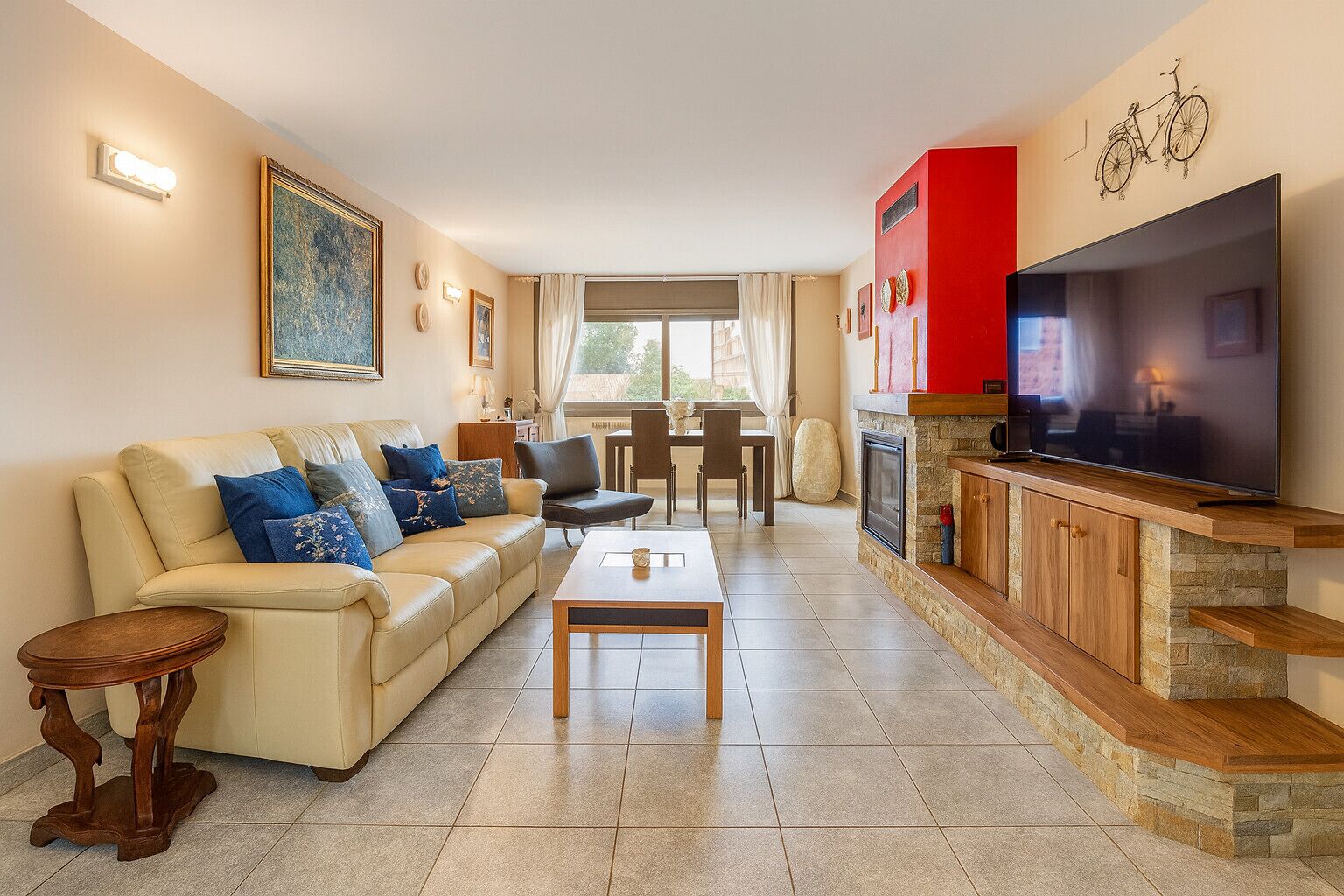 A living room with a sofa, coffee table, TV, and stone fireplace.