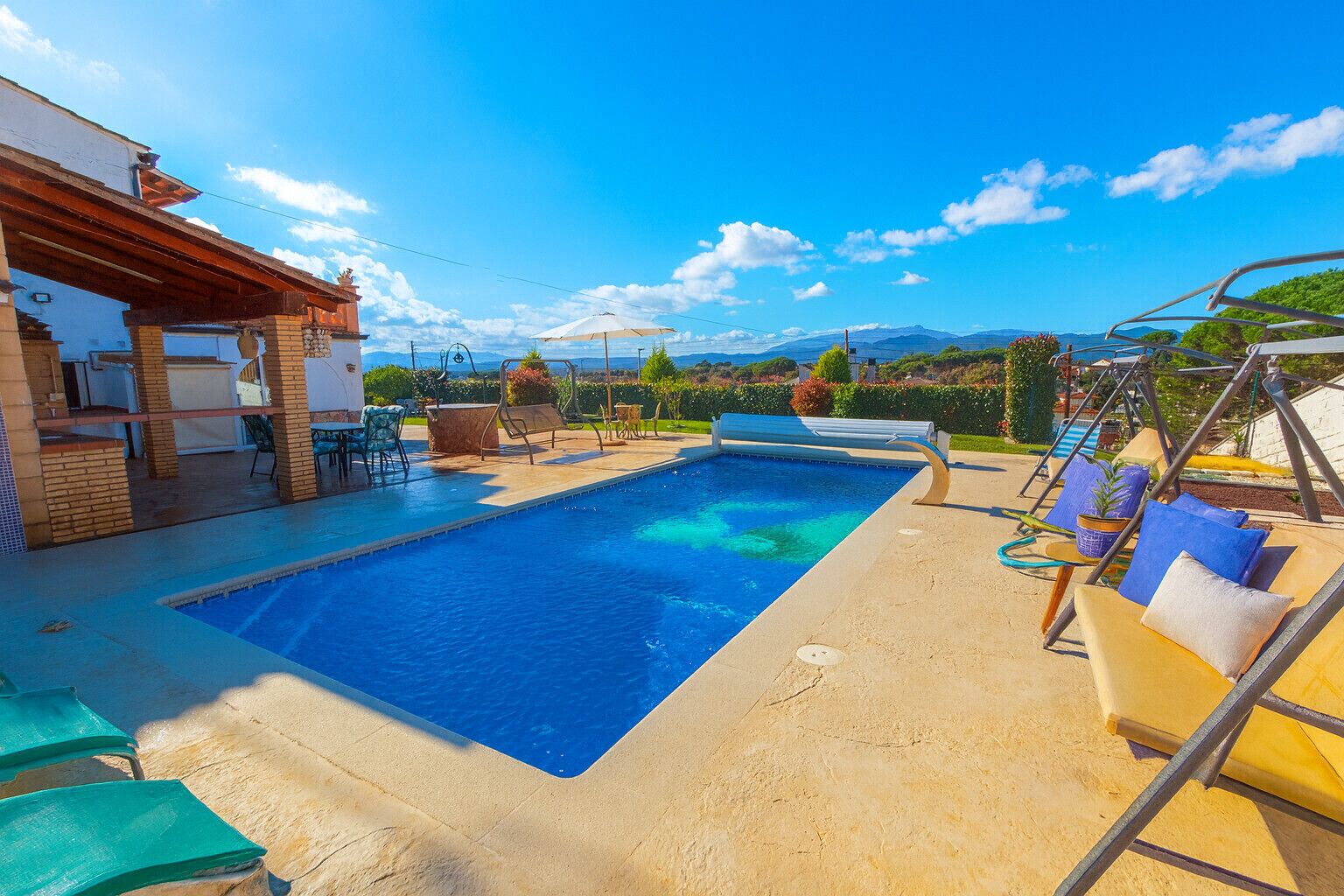 A swimming pool with lounge chairs and a pergola.